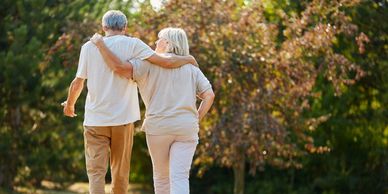 Elderly couple walking arm in arm in a park.