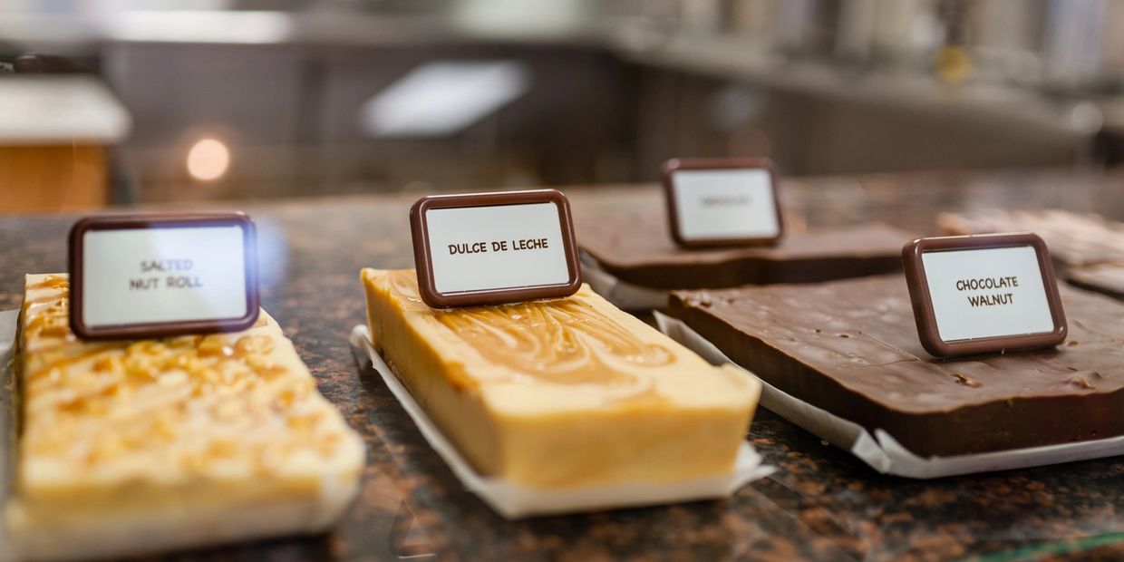 Assorted fudge varieties labeled and displayed on a counter.