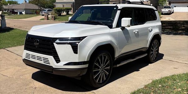 White Lexus SUV parked on a residential driveway under sunlight.