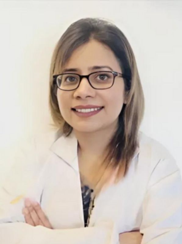 Smiling woman wearing glasses and a white coat.