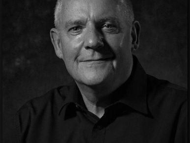 Black and white portrait of an older man with a gentle smile.