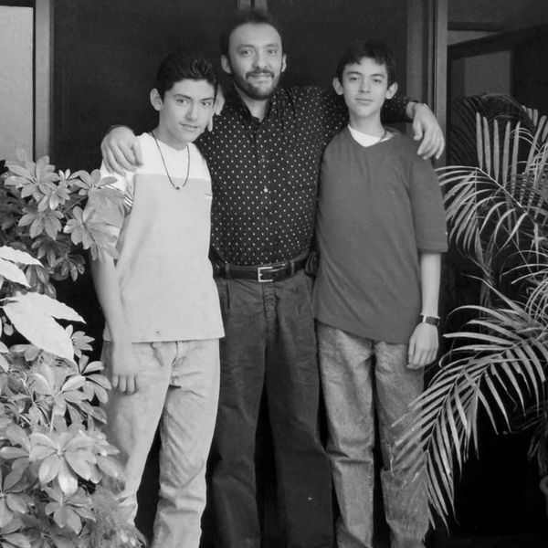 Three males posing together, arms around each other, smiling for the camera.