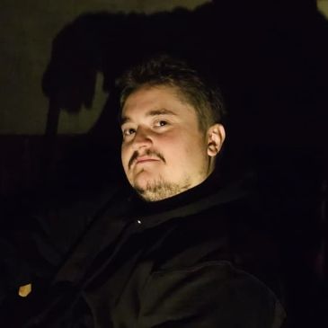 Man sitting in dark with a large shadow behind him.
