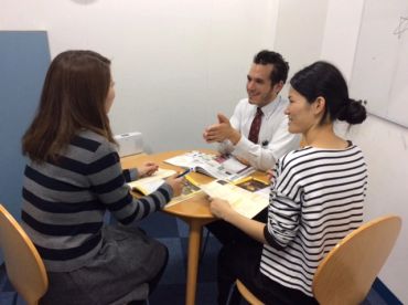 Three people engaged in a discussion around a table with documents.