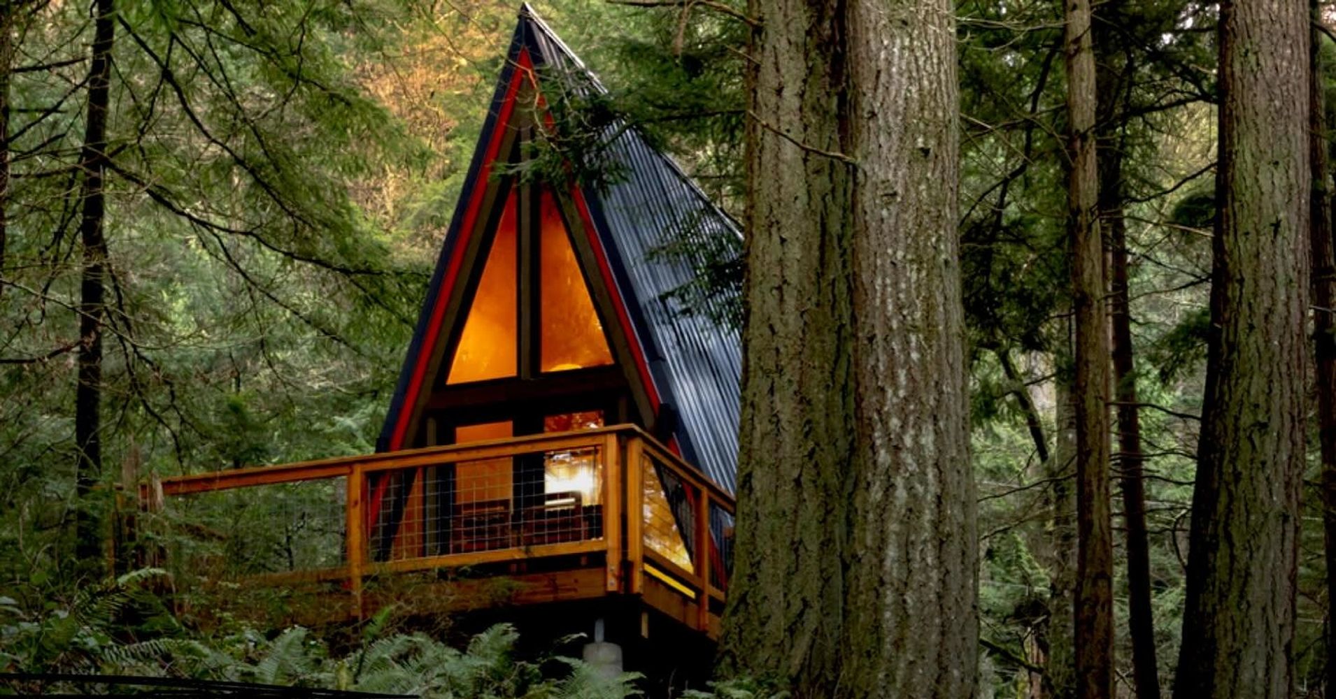 A cozy A-frame cabin glowing warmly in a dense forest.