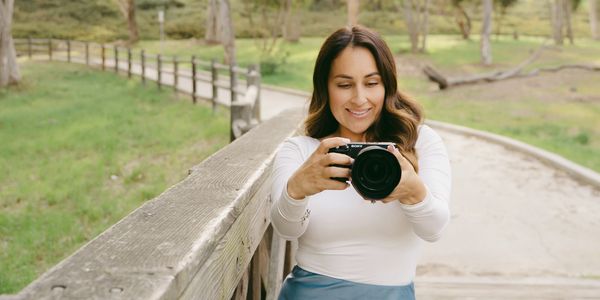 photo of a woman holding a camera and looking through the lens