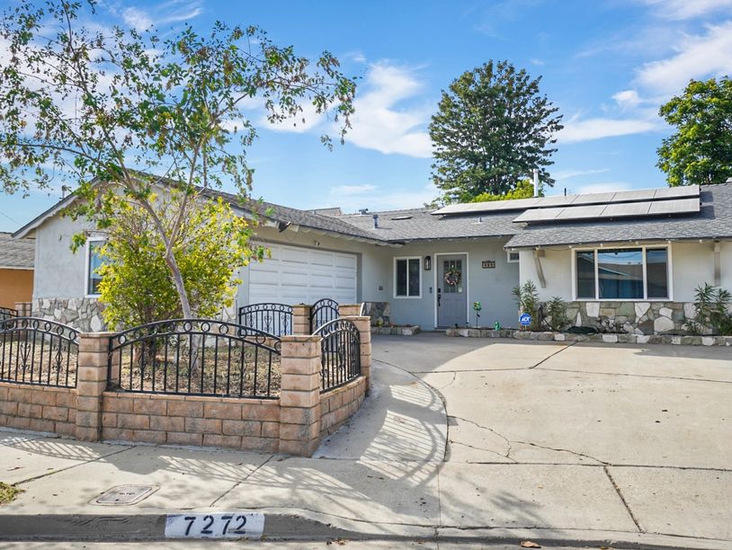Single-story house with solar panels and fenced front yard.