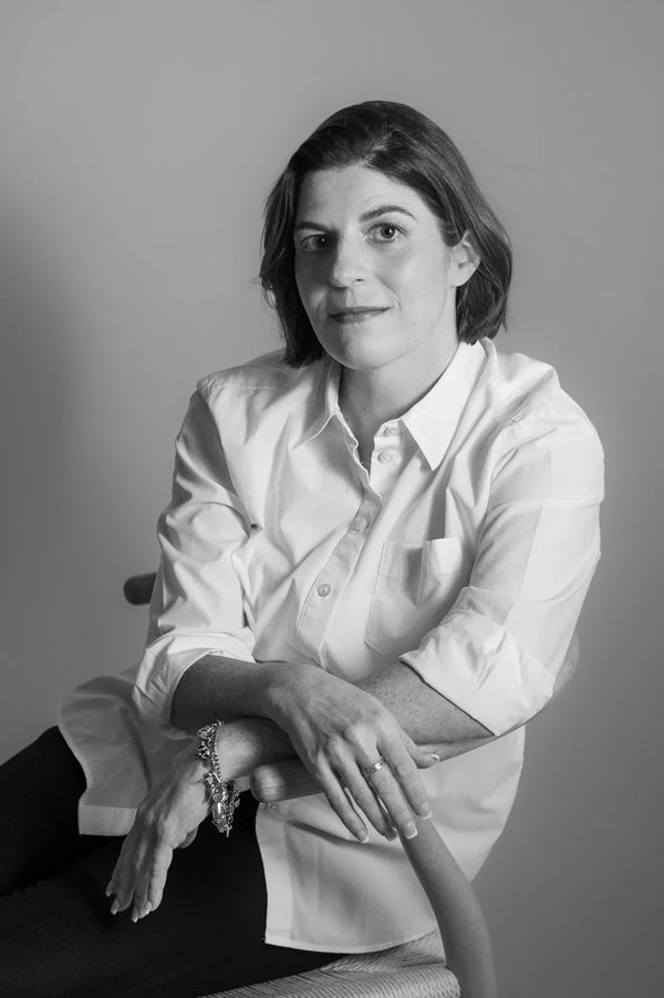 Black and white portrait of a woman in a white shirt sitting on a chair.
