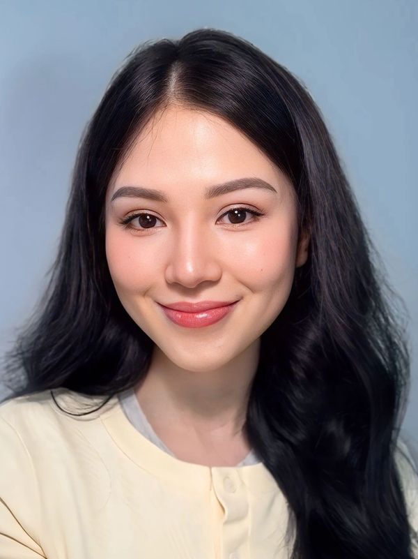 Portrait of a smiling young woman with long black hair and natural makeup.