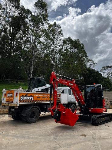 Red excavator next to a truck in a construction area.