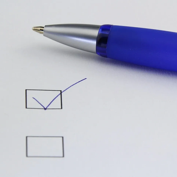 Picture of a writing pen with check mark on paper.
