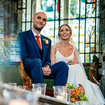 Newlywed couple sitting together in a church, smiling happily.