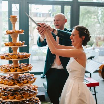 Bride and groom joyfully cutting their wedding cupcake tower together.