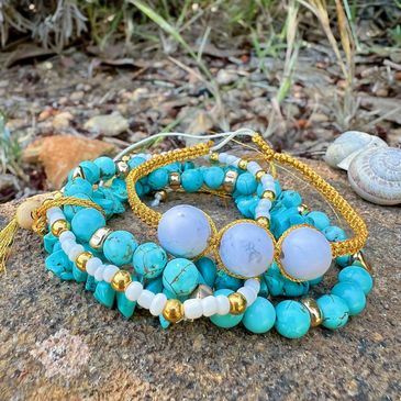 Turquoise and gold beaded bracelets arranged on a rock outdoors.