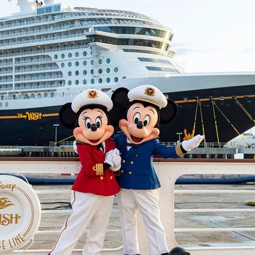 Mickey and Minnie Mouse dressed as ship captains in front of Disney Wish cruise ship.