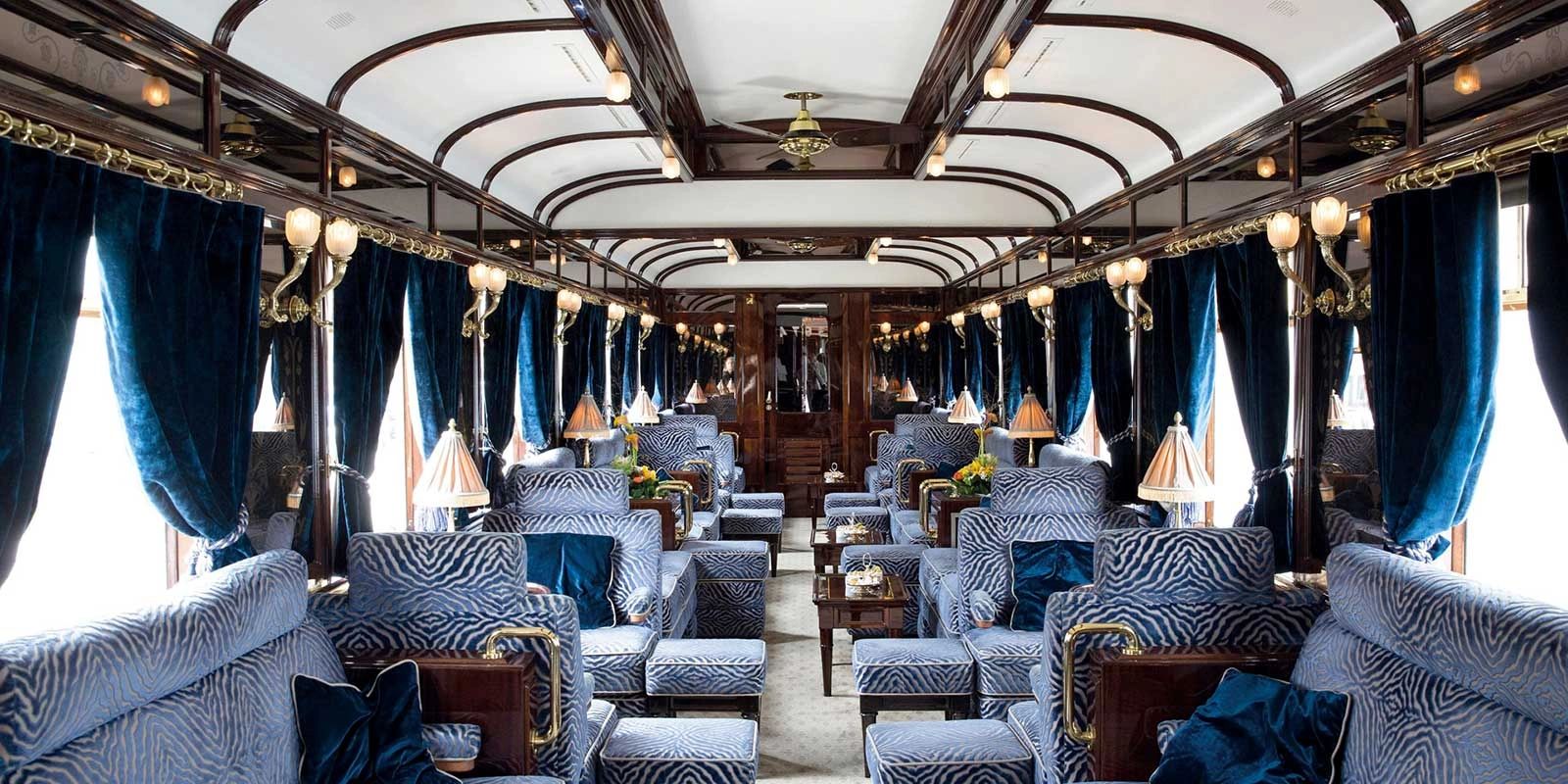 Luxurious vintage train carriage with plush blue seating and elegant decor.