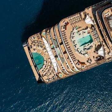 Aerial view of a luxury cruise ship with pools and deck chairs.