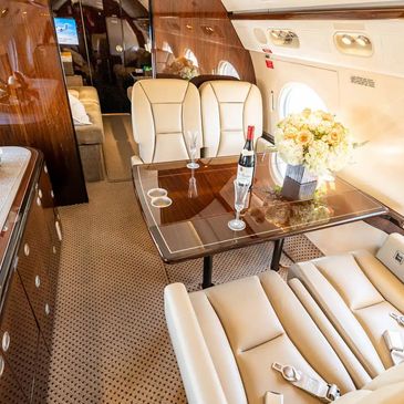 Luxurious private jet interior with leather seats and a wine setup.