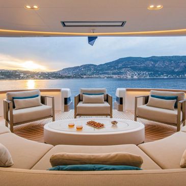 Luxury yacht seating area with sunset sea view and refreshments.