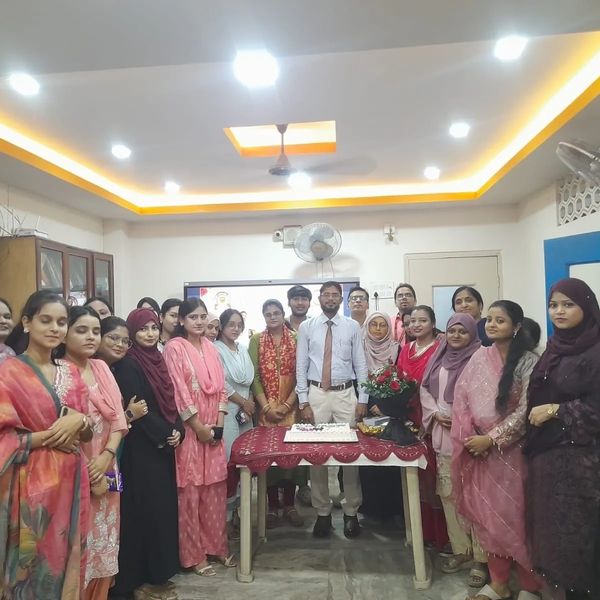 Group photo of people around a table with a cake.