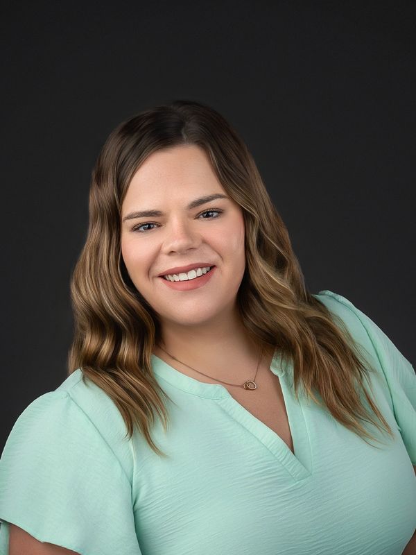Smiling woman with wavy hair in mint green top.