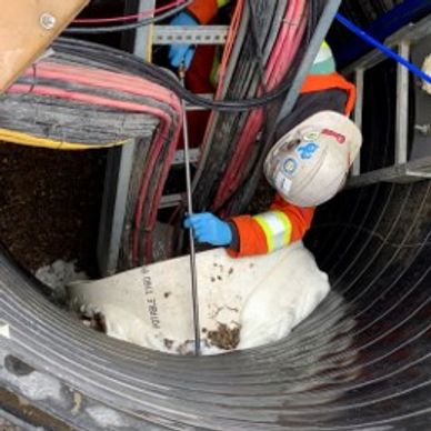 Technician finishing foam seal around manhole pipe to prevent infiltration and stop soil intrusion.
