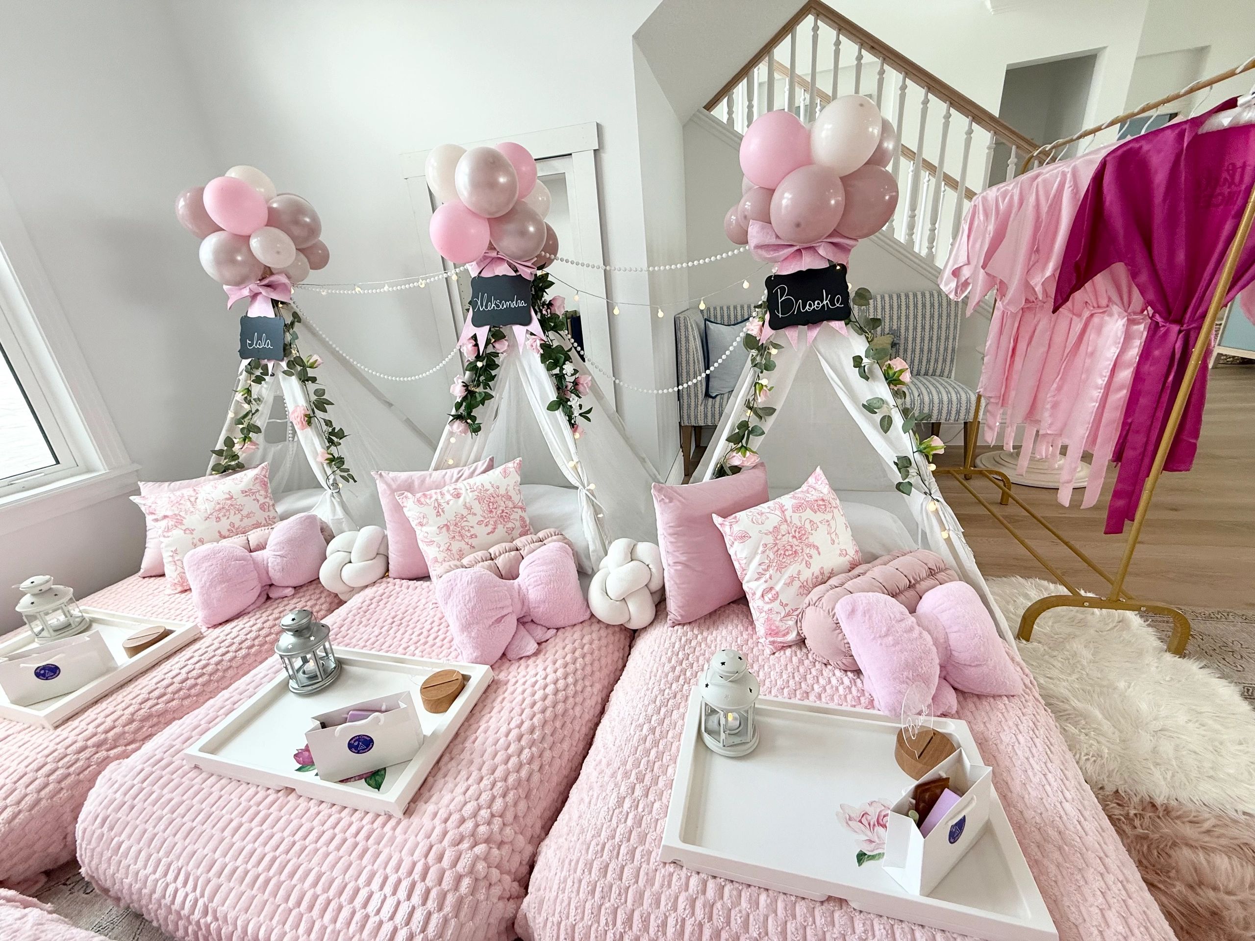 Cozy pink-themed sleepover setup with decorated tents and personalized name tags.