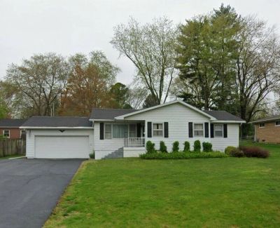 Single-story white house with a two-car garage and a spacious green lawn.