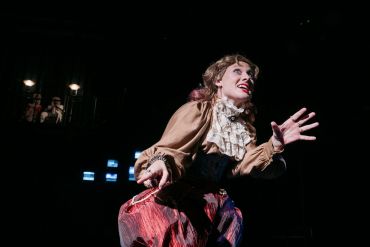 Actress performing dramatically on stage in vintage costume.