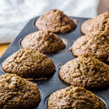 Freshly baked muffins in a muffin tin on a wooden surface.