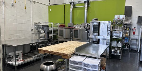 A clean, organized commercial kitchen with stainless steel appliances and worktables.