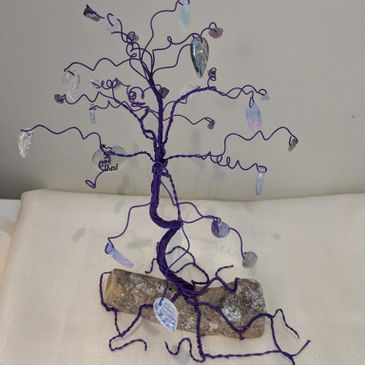 A decorative purple wire tree with translucent leaf ornaments on a stone base.