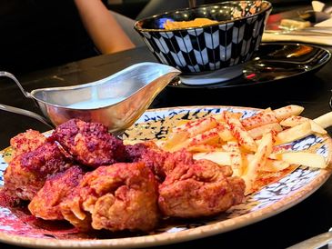 Plate of fried chicken and seasoned fries with dipping sauce on the side.