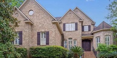 Large brick house with multiple windows and a well-maintained garden.