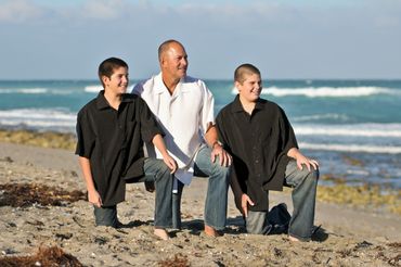 Father and Son Portrait of them kneeling on the beach sand and looking out at sea.