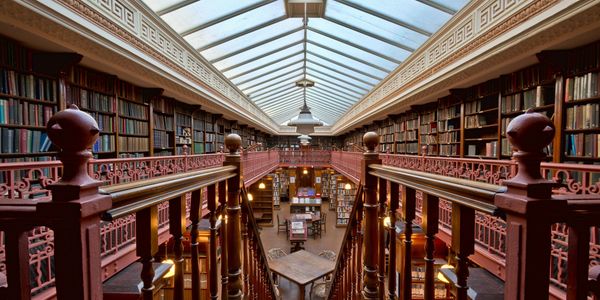 Interior view of a classic library with wooden stairs and bookshelves in Leeds City Center