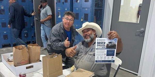 Two men at a driver appreciation event, one holding a flyer.