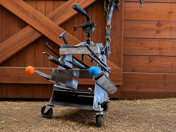 A metal contraption with colorful handles on wheels in front of a wooden door.