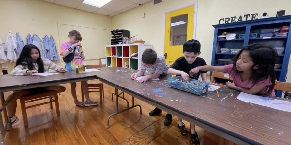Children engaged in art activities in a classroom with colorful supplies.