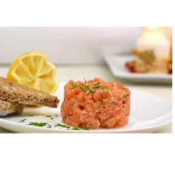 Salmon tartare served with lemon and toasted bread slices.
