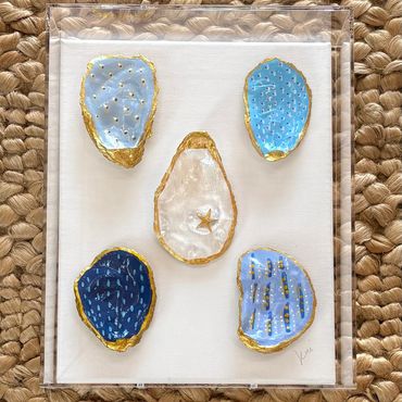 Five artistic painted oyster shells with gold accents.