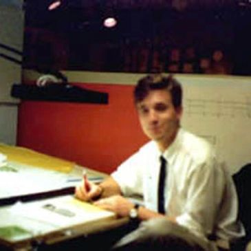Man in white shirt working at a drafting table.