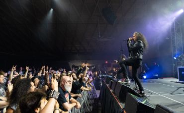 Rock singer performing energetically to a lively crowd at a concert.