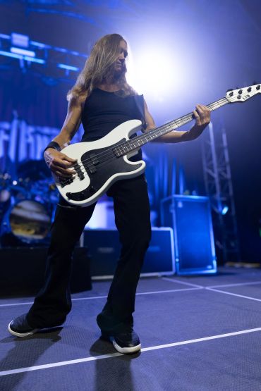 Musician playing bass guitar on stage with dramatic lighting.