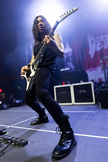 Guitarist passionately playing electric guitar on stage during a live performance.