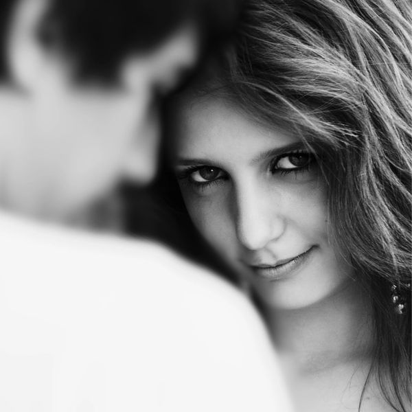 Black and white phoot of girl smirking at camera over a guy's shoulder