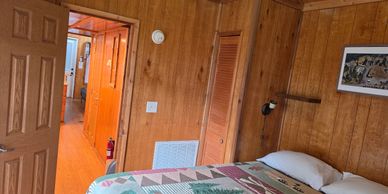 Cozy wooden cabin bedroom with a patterned quilt and warm lighting.
