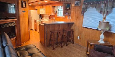 Cozy wood-paneled living space with kitchen bar and stools.