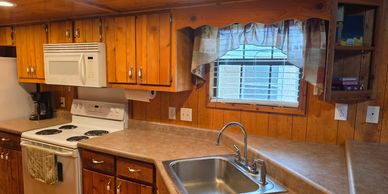 Cozy kitchen with wooden cabinets, white appliances, and a window above the sink.