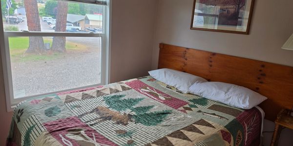 Cozy bedroom with rustic quilt and window view of trees and buildings.